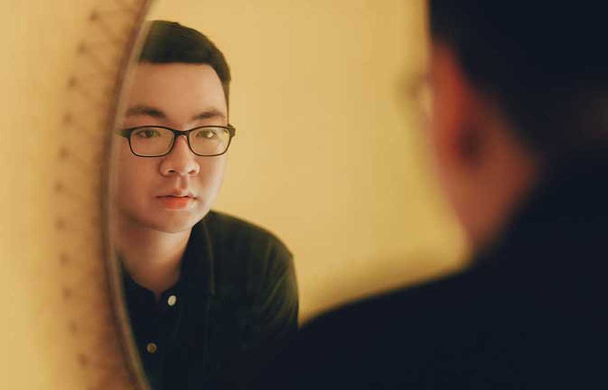 Man with glasses looking into the mirror, photofeeler blog header image